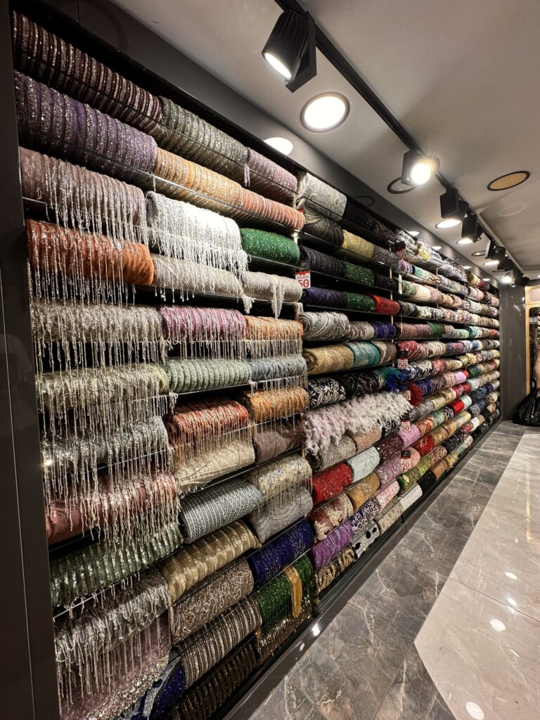 Luxury showroom displaying a wide collection of embroidered lace, sequined, tulle, satin, and couture fabrics in various colors for haute couture fashion